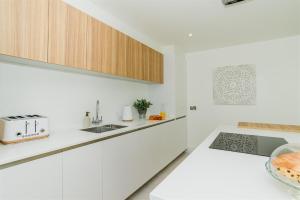 a kitchen with white cabinets and a sink at 7 Cliff Edge in Newquay