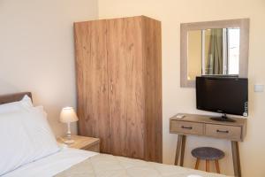 een slaapkamer met een bed en een televisie op een houten kast bij John's Studios in Karavomylos