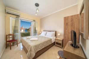 a bedroom with a bed and a tv and a window at John's Studios in Karavomylos