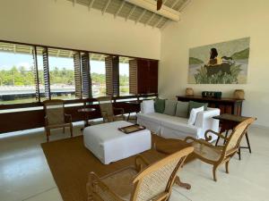 a living room with a couch and chairs and windows at Sitara Weligama in Weligama