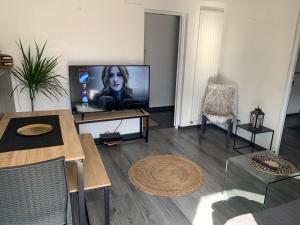 uma sala de estar com uma televisão de ecrã plano e uma mesa em Appartement detox au pied du semnoz em Seynod