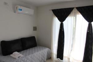 a bedroom with a couch and a tie on a window at CN departamentos in Guaymallen