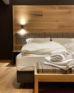 a bedroom with a large white bed with a wooden headboard at Hotel Rech-Hof Sayonara in Folgaria