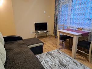 - un salon avec une table et une télévision dans l'établissement Arda Riverside Apartment, à Kardjali
