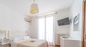 a white bedroom with a bed and a flat screen tv at Il Pappagallo in Leuca