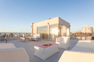 a rooftop patio with white chairs and a table at 20 Hotel in Punta del Este