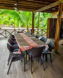 a wooden table and chairs on a deck with trees at playa mecana kirita in Bahía Solano