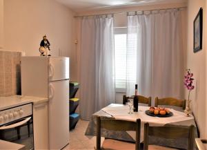 a kitchen with a table and a white refrigerator at Apartments Panorama view Zeljko Scerbe in Rab