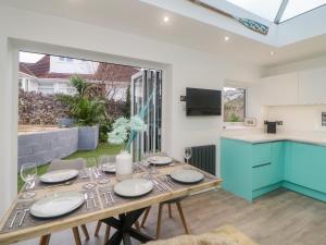 a dining room with a table and a kitchen at Ingledene in Brixham