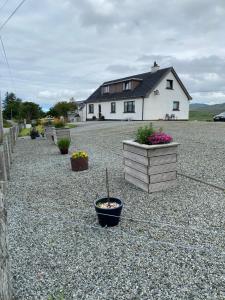 a house with potted plants on a gravel driveway at Almondbank Self Catering Apartment in Skeabost