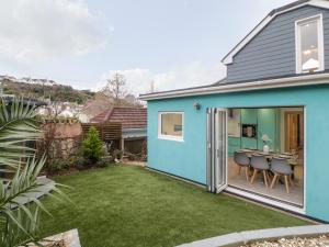 een blauw huis met een tuin met een tafel en stoelen bij Ingledene in Brixham