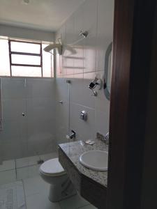 a bathroom with a toilet and a sink and a shower at Hotel Santa Fé in Ponta Grossa