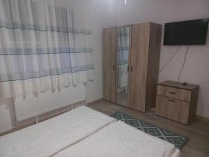 a bedroom with a bed and a cabinet and a television at City Center Flat in Odorheiu Secuiesc