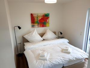 ein weißes Bett mit zwei weißen Handtüchern darauf in der Unterkunft 47 7 Mehrblick in Wangerland