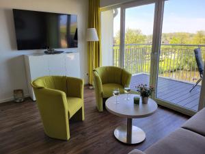 uma sala de estar com 2 cadeiras, uma mesa e uma varanda em 47 3 M Seestern em Wangerland