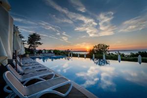 a swimming pool with lounge chairs and a sunset at Eve Santa Marina Apartment II - sea, pools, relax in Sozopol