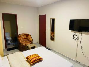 a room with a bed and a tv and a chair at Résidence Karamel Yaoundé Anguissa in Yaoundé