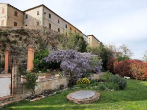 a garden in front of a building with purple flowers at Corte Landriani in Montefelcino