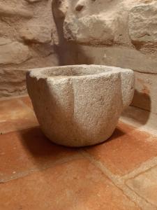 uma tigela de pedra sentada no chão ao lado de uma parede de pedra em Corte Landriani em Montefelcino
