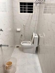 La salle de bains blanche est pourvue de toilettes et d'une fenêtre. dans l'établissement Izi Airport Stay, à Chennai