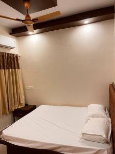 a bedroom with a white bed with a ceiling fan at Izi Airport Stay in Chennai