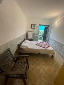 Schlafzimmer mit einem Bett, einer Bank und einem Fenster in der Unterkunft Hotel Central Praia in Tramandaí
