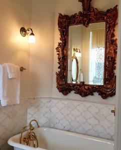 een badkamer met een grote spiegel en een bad bij The Queen On Main in Winters