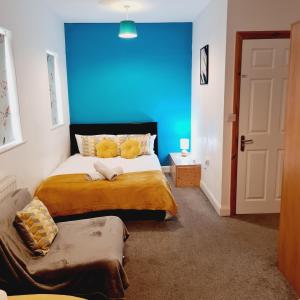 a bedroom with a large bed with a blue wall at Sheridan House I Long or Short Stay I Special Rate Available in Derby