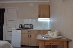 a kitchen with a white refrigerator and a table at Студия №1 LifeHouseAlmaty в ЖК Теремки-2 in Almaty