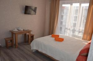 a bedroom with a bed with a small table and a window at Студия №1 LifeHouseAlmaty в ЖК Теремки-2 in Almaty