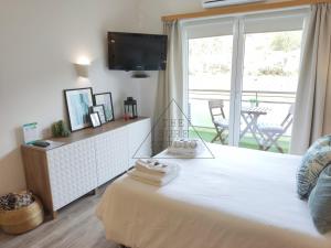 a bedroom with a bed with a television and a balcony at The Surf Studio - Ericeira in Ericeira