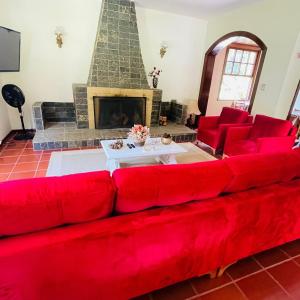a red couch in a living room with a fireplace at Sitio do Imbuí em Teresópolis in Teresópolis