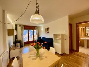 una sala de estar con una mesa con un jarrón de flores. en Bosquet, El Forn, en Canillo