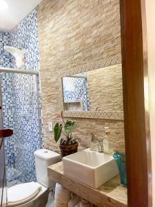 La salle de bains est pourvue d'un lavabo blanc et de toilettes. dans l'établissement Casa Temporada Trancoso, à Trancoso