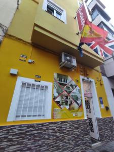アリカンテにあるhostal olozagaの窓と看板が付いた黄色い建物
