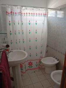 a bathroom with a shower curtain with a sink and a toilet at Dpto Santa Rosa in Santa Rosa de Calamuchita
