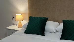 een bed met twee groene kussens en een lamp op een tafel bij Wallada Valdenebro in Córdoba