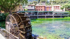 a river with a water wheel in front of a building at Luberoom in Cavaillon