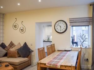a living room with a table and a clock on the wall at Fionas Cottage in Crieff