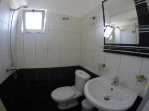a bathroom with a white toilet and a sink at Hotel Arsenal in Ksamil