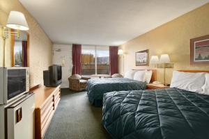 a hotel room with two beds and a television at Ramada by Wyndham Roanoke in Roanoke