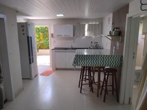 cocina con encimera con taburetes y nevera en Sossego da ilha 02, en Florianópolis