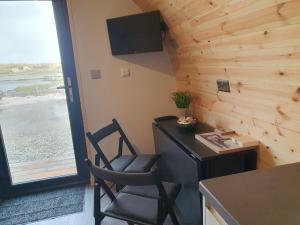 a kitchen with a table and a chair and a window at Grimsay Glamping, North Uist - Pod Ruadh in Rossinish
