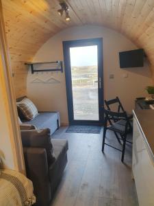 een woonkamer met een bank en een deur met een raam bij Grimsay Glamping, North Uist - Pod Ruadh in Rossinish