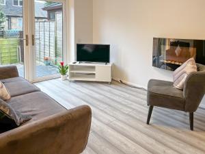 sala de estar con sofá y TV en Devonshire Nook, en Chinley