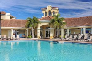 a pool in front of a house with chairs and a building at Brand New Modern Vista Cay Reserve Condo - 5003 in Orlando