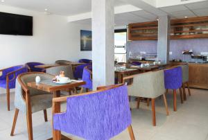 a restaurant with purple chairs and tables and a tv at Rives d'Or Hôtel in La Seyne-sur-Mer