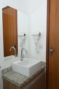 La salle de bains est pourvue d'un lavabo blanc et d'un miroir. dans l'établissement Otimo apto c piscina e Wi Fi em Caldas Novas GO, à Caldas Novas