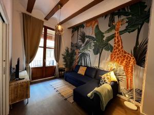 a living room with a blue couch and a giraffe mural at El negrito, apartamento centro in Valencia