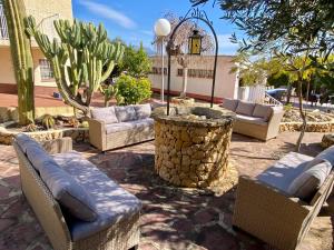 une terrasse avec des chaises en osier, une table et une fontaine dans l'établissement Gran Villa La Marina, à Polop